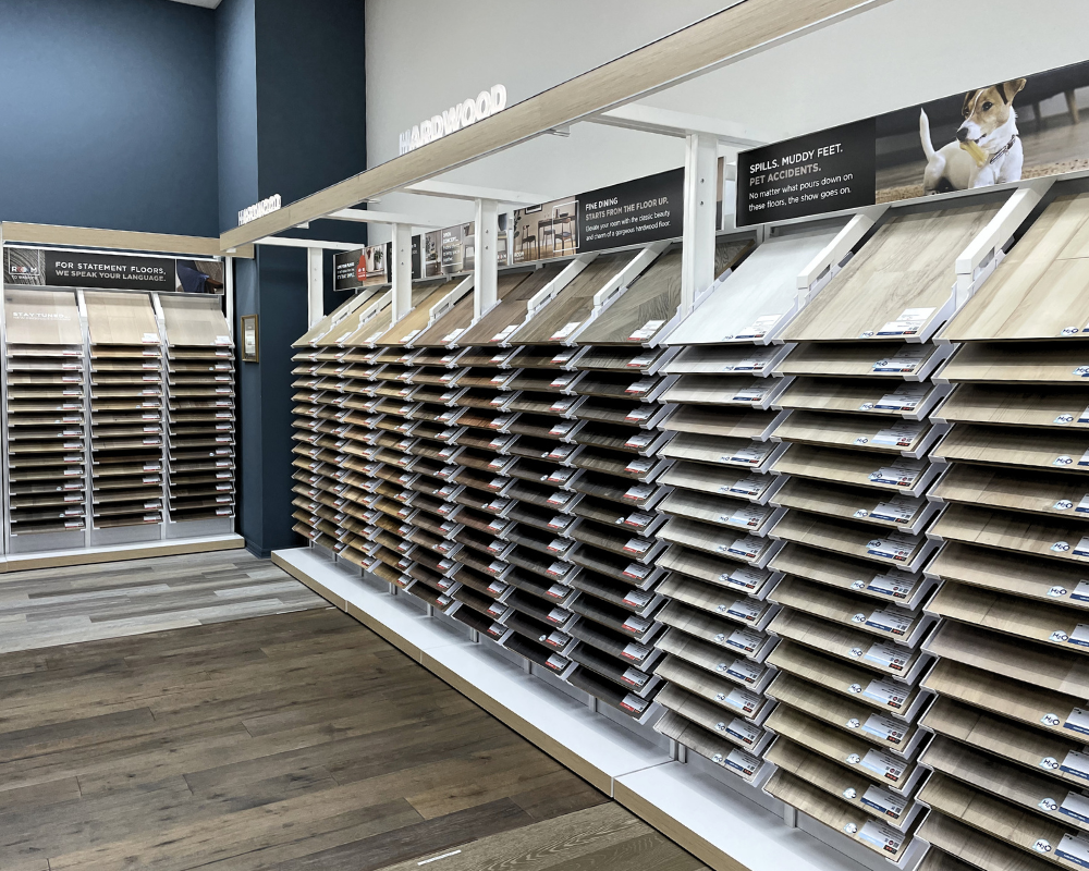 A display of various wood flooring samples in our showroom, organized on tiered racks.